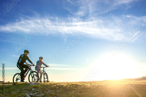 Happy mountainbike couple outdoors have fun together on a summer afternoon sunset