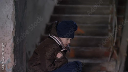 frozen wary boy is warming in a dilapidated old house photo