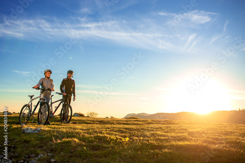 Happy mountainbike couple outdoors have fun together on a summer afternoon sunset