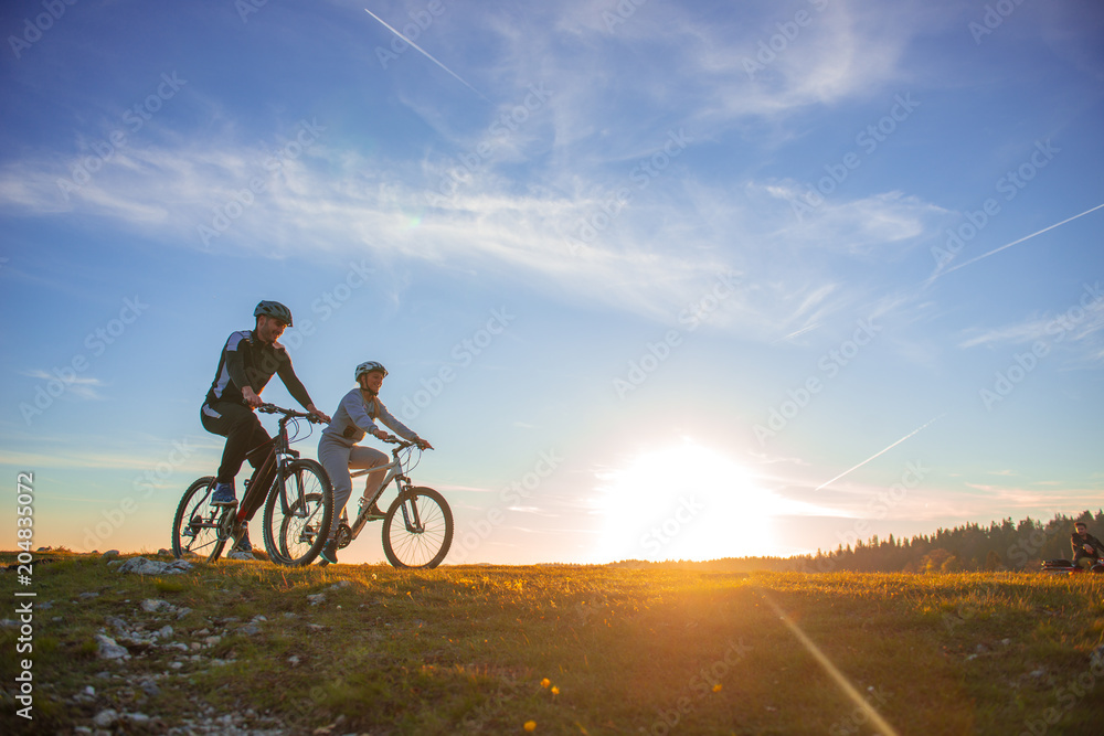 Obraz premium Happy mountainbike couple outdoors have fun together on a summer afternoon sunset