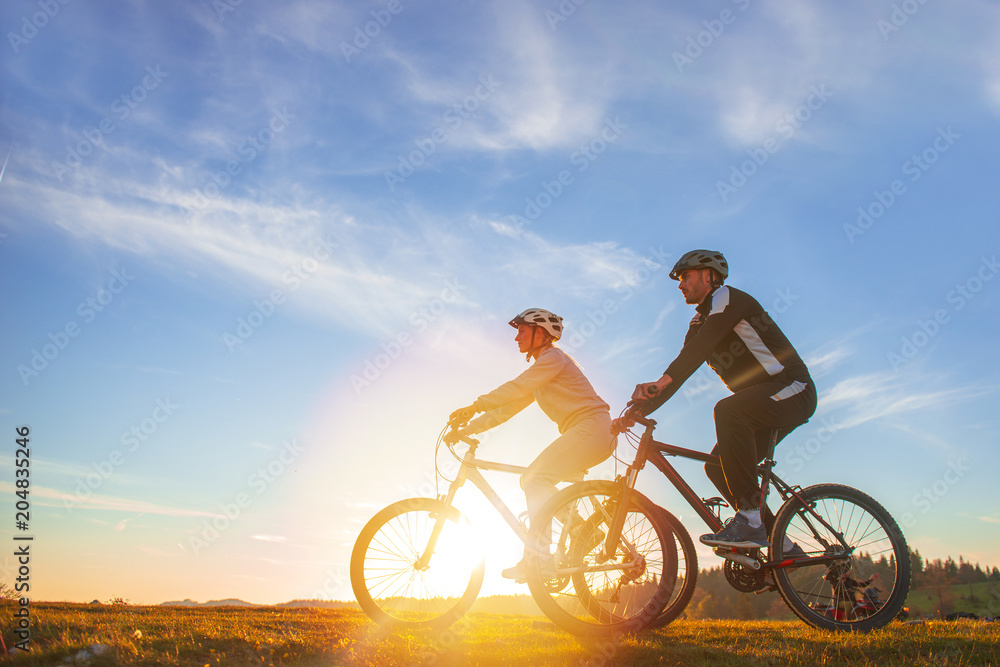 Fototapeta premium Happy mountainbike couple outdoors have fun together on a summer afternoon sunset