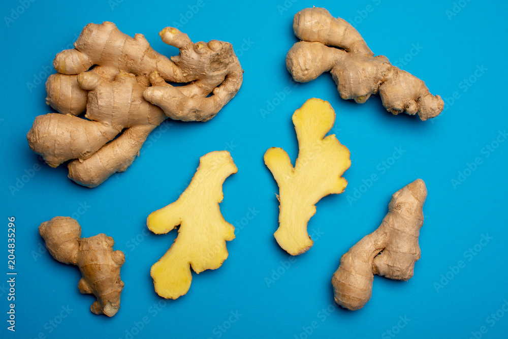 Fototapeta premium Trendy food flat lay concept on blue background with fresh big ginger root close up copy space isolated