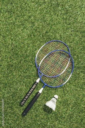 top view of badminton rackets and shuttlecock on green grass