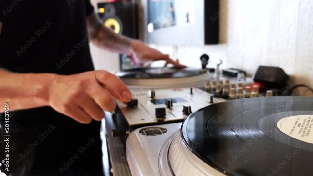 Mix and scratch, hands of a DJ on vinyl and mixer knobs. Close up of hands of DJ plays music mixing and scratching on turntable music equipment. Mix and scratch, hands of a DJ on vinyl and mixer knobs. Close up of hands of DJ plays music mixing and scratching on turntable music equipment.