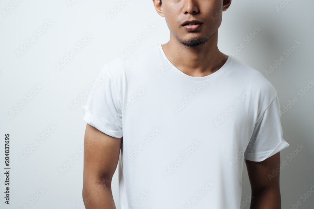 Obraz premium Young guy wearing white blank t-shirt, empty wall, horizontal studio close-up