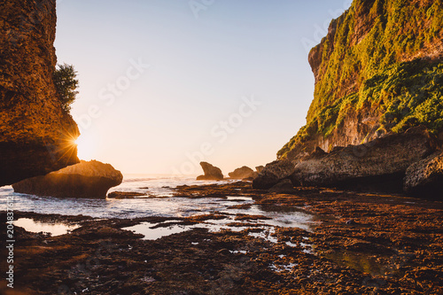 Cliff with rocks, stones, low tide ocean and sunset colors in Bali