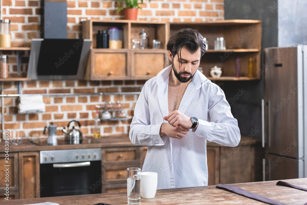 handsome loner businessman checking time in morning at kitchen handsome loner businessman checking time in morning at kitchen