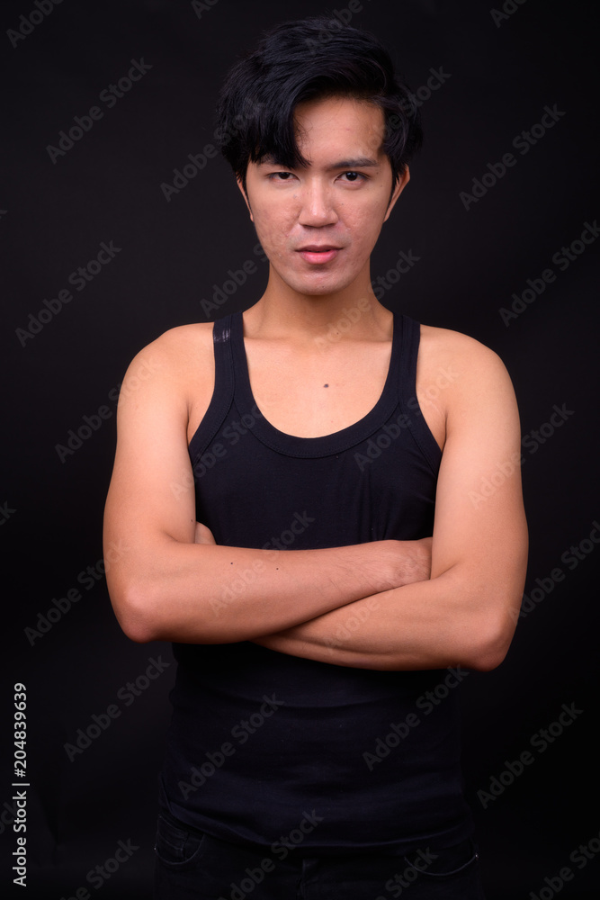Young handsome Asian man against black background Young handsome Asian man against black background