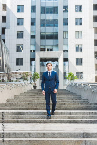 stylish young businessman walking down stairs in business district