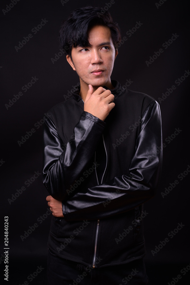 Fototapeta premium Young handsome Asian man against black background