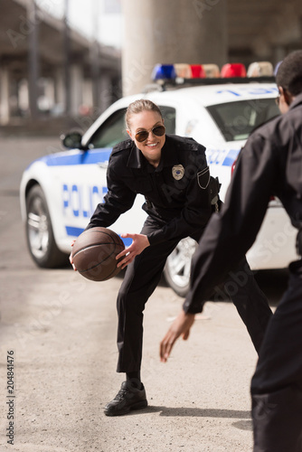 active young police officers playing basketball on street