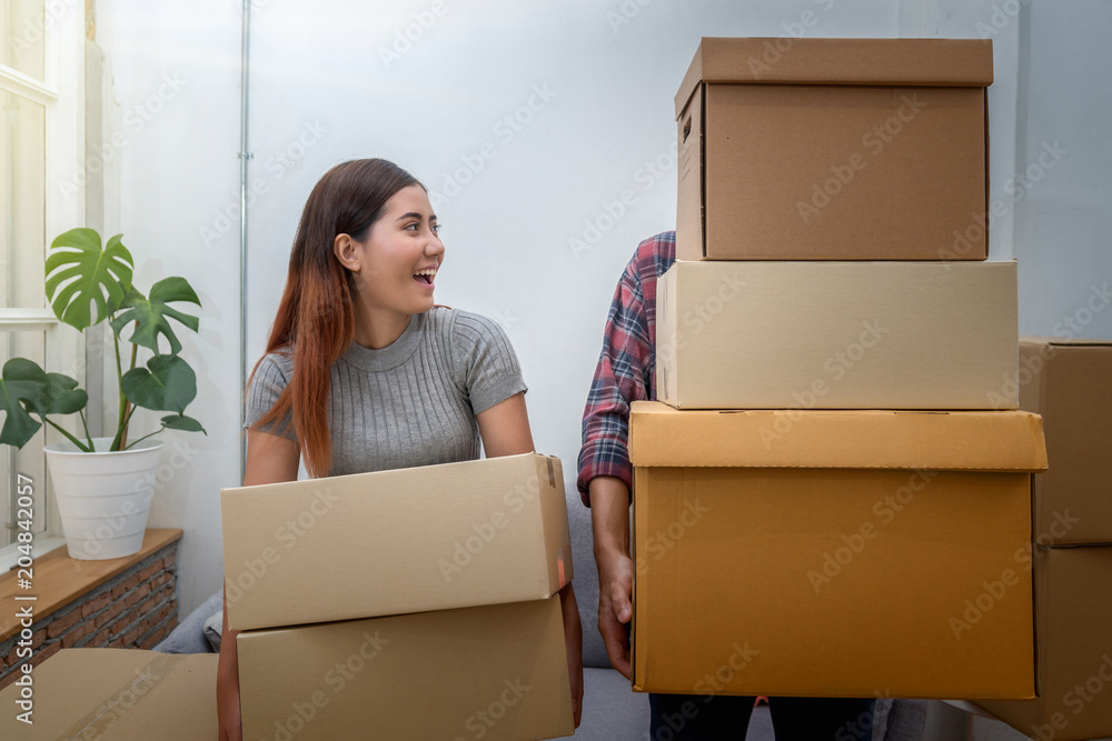 Asian young couple carrying big cardboard box for moving in new house, Moving and House Hunting concept Asian young couple carrying big cardboard box for moving in new house, Moving and House Hunting concept
