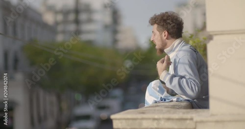 Happy Argentinian football supporter waving jersey while celebrating victory in balcony