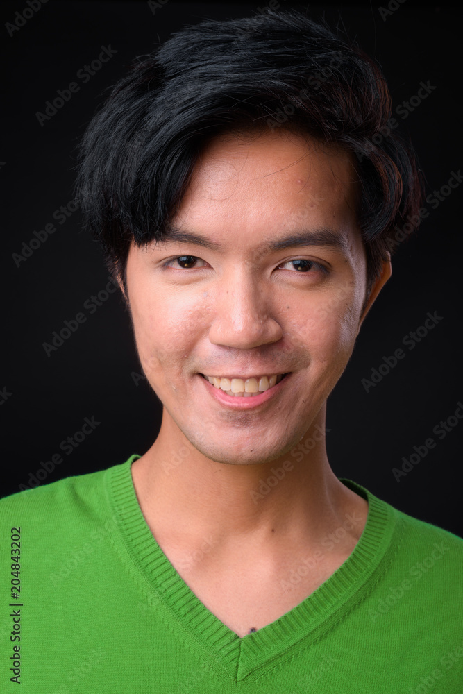 Young handsome Asian man against black background Young handsome Asian man against black background