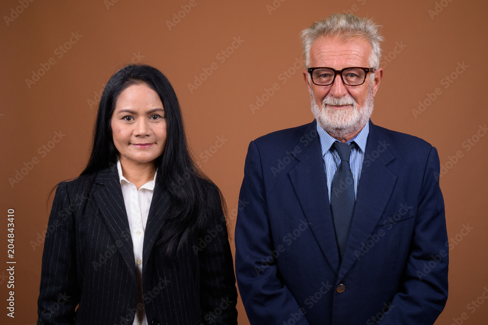 Mature multi-ethnic business couple against brown background Mature multi-ethnic business couple against brown background