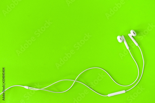 White Earphone on green background, Copy space. Music is my life concept