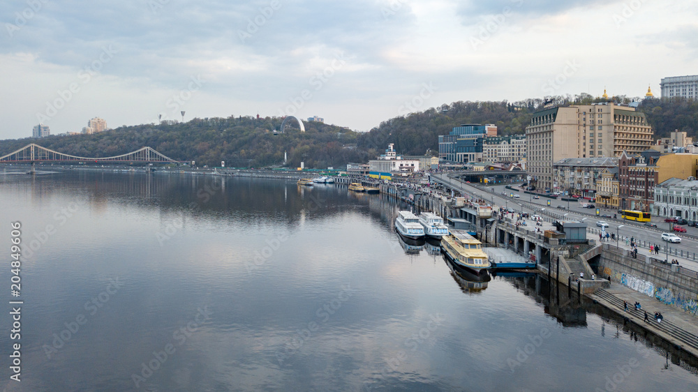 View of the pedestrian bridge, the Vladimirskaya Hill with the monument of the Arco-Soviet of the People, the river Dnipro and tourist parades in Kyiv