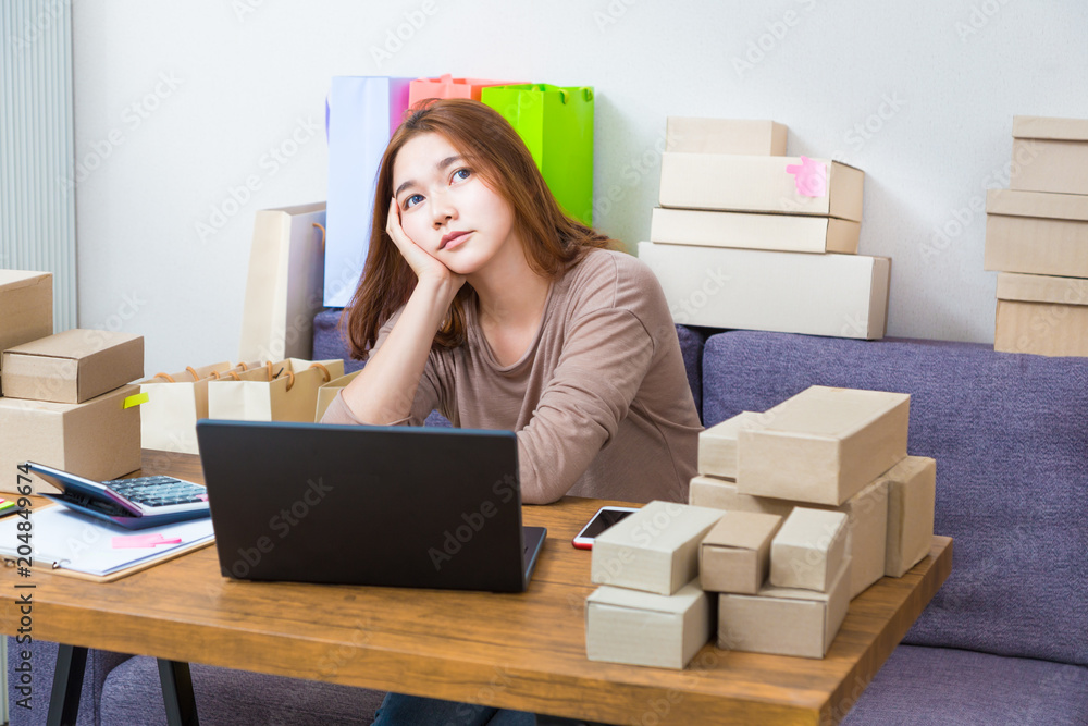 Young asian online seller businesswoman working at home taking a rest from working on her online orders and thinking about her business future Young asian online seller businesswoman working at home taking a rest from working on her online orders and thinking about her business future