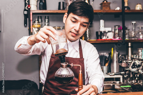 Handsome barista making coffee on syphon coffee maker in the cafe