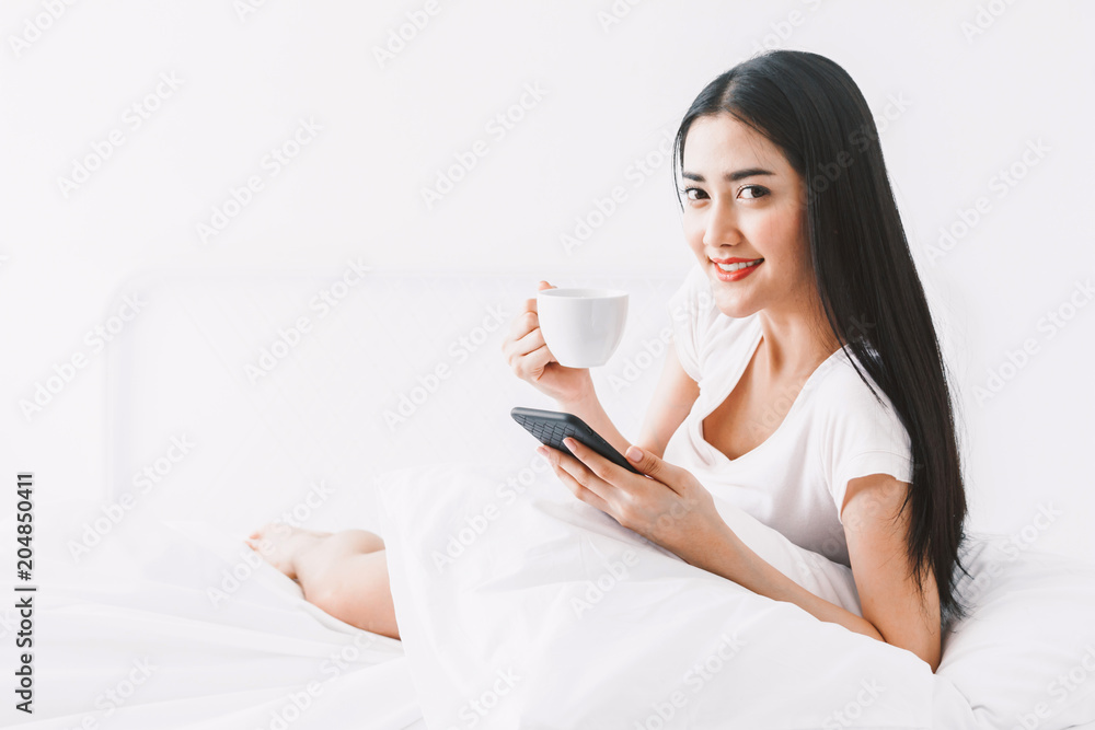 Happy woman relaxing and using smartphone on the bed at home.woman checking social apps with smartphone Happy woman relaxing and using smartphone on the bed at home.woman checking social apps with smartphone