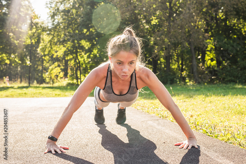 Fototapeta Naklejka Na Ścianę i Meble -  Fitness woman doing push-ups during outdoor cross training workout. Beautiful young and fit fitness sport model training outside in park