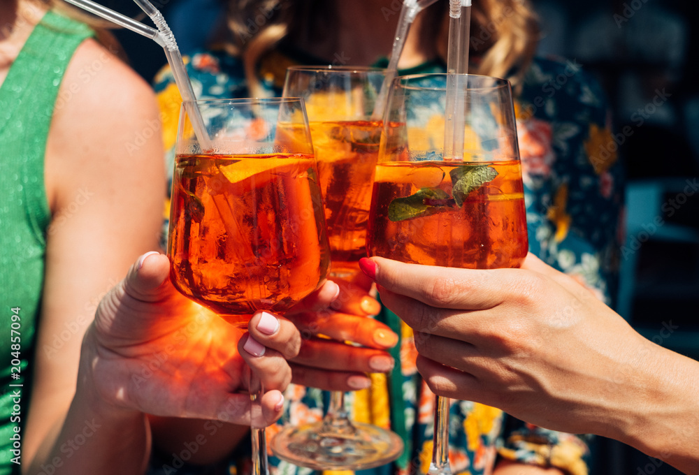Woman hands toasting glasses with aperol spritz
