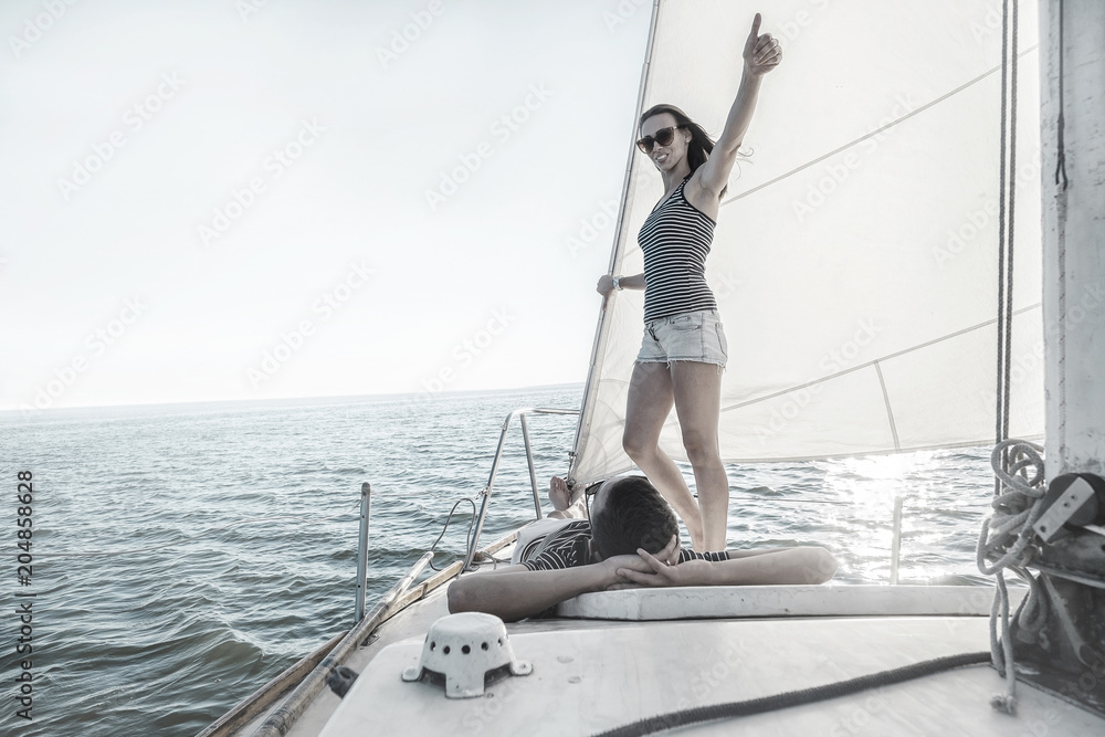 Romantic couple in love on sail boat at sunset under sunlight