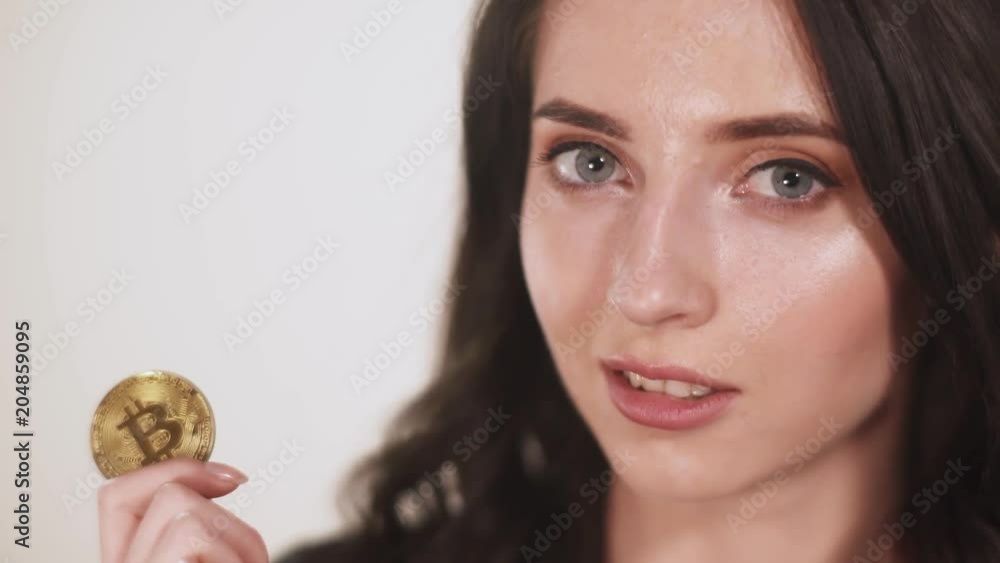 Girl, holds bitcoin coin in teeth, white background.
Girl, holds bitcoin coin in teeth, white background.