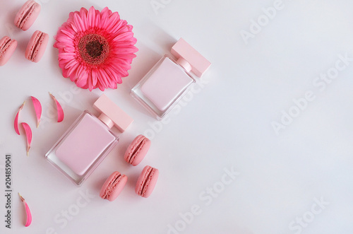 Beautiful perfume bottle with pink flowers and macaroons. Luxury perfumery background with copy space. Sweet and Floral fragrance concept.