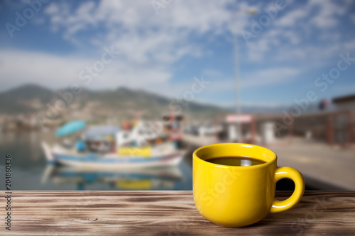 Yellow cup with tea on wooden table opposite a defocused background. Collage. Selective focus