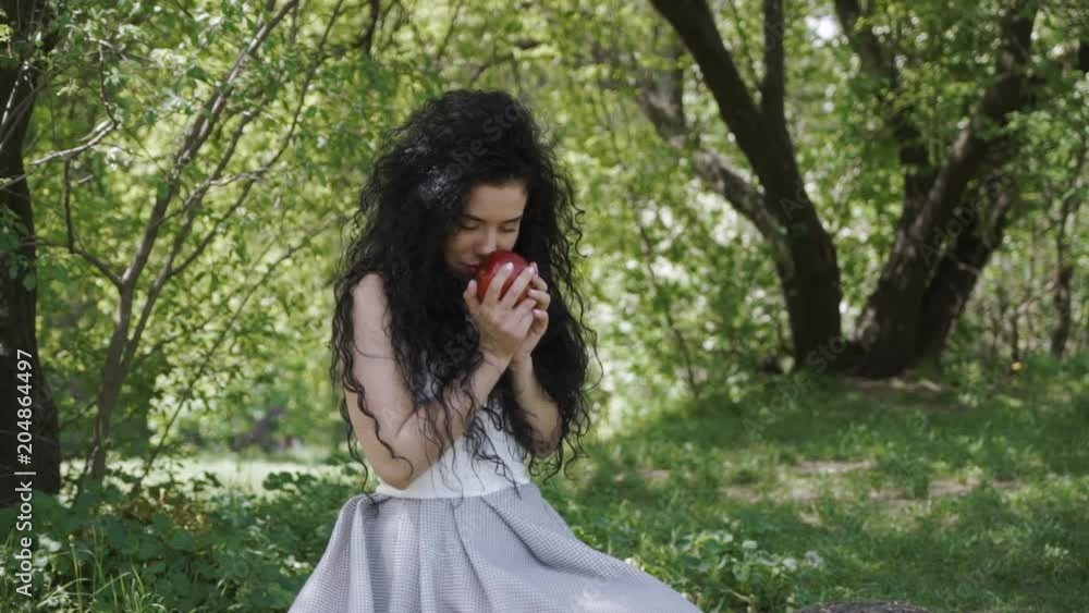 Beautiful woman in blue dress enjoy a smell of fresh red apple Beautiful woman in blue dress enjoy a smell of fresh red apple