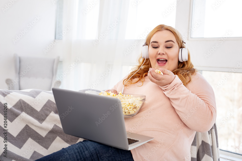 Great film. Joyful stout woman watching a film and eating popcorn Great film. Joyful stout woman watching a film and eating popcorn