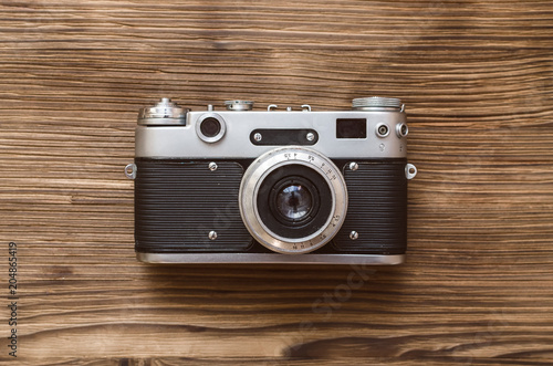 Old film photo camera isolated on brown wooden background.