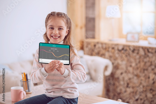 Future financier. Positive smart girl smiling while using a banking app
