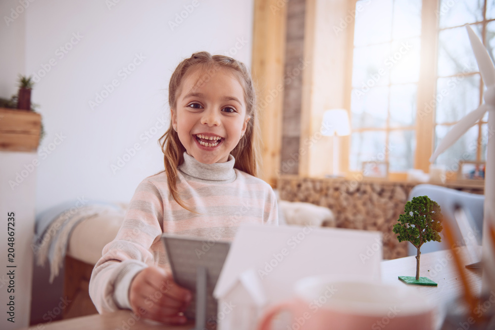 Wonderful mood. Cheerful happy girl looking at you while holding a solar battery Wonderful mood. Cheerful happy girl looking at you while holding a solar battery