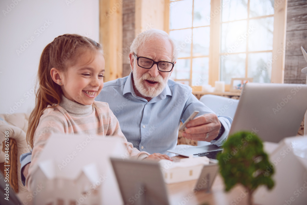 Home schooling. Positive aged man sitting near his pupil while giving her a lesson Home schooling. Positive aged man sitting near his pupil while giving her a lesson