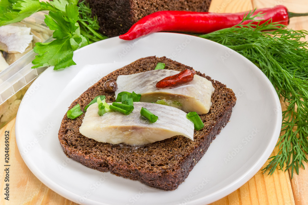 Open sandwich with pickled herring slices on brown bread closeup Open sandwich with pickled herring slices on brown bread closeup