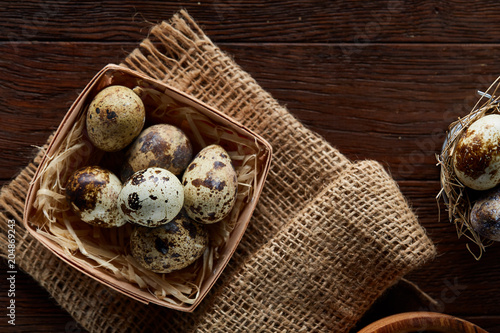 Rustic still life with quail eggs in bucket, box and bowl on a linen napkin over wooden background, selective focus