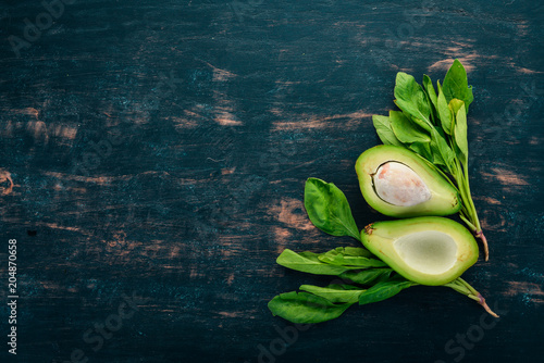 Fresh avocado and spinach. On a wooden background. Healthy food. Top view. Copy space.