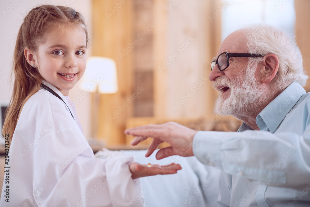 Dream job. Delighted positive girl smiling while giving a pill to her patient Dream job. Delighted positive girl smiling while giving a pill to her patient