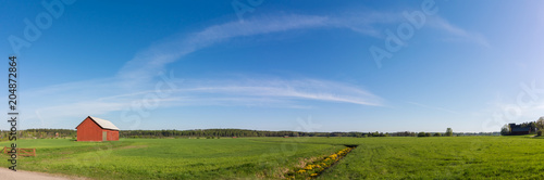 Green field panorama with red barn