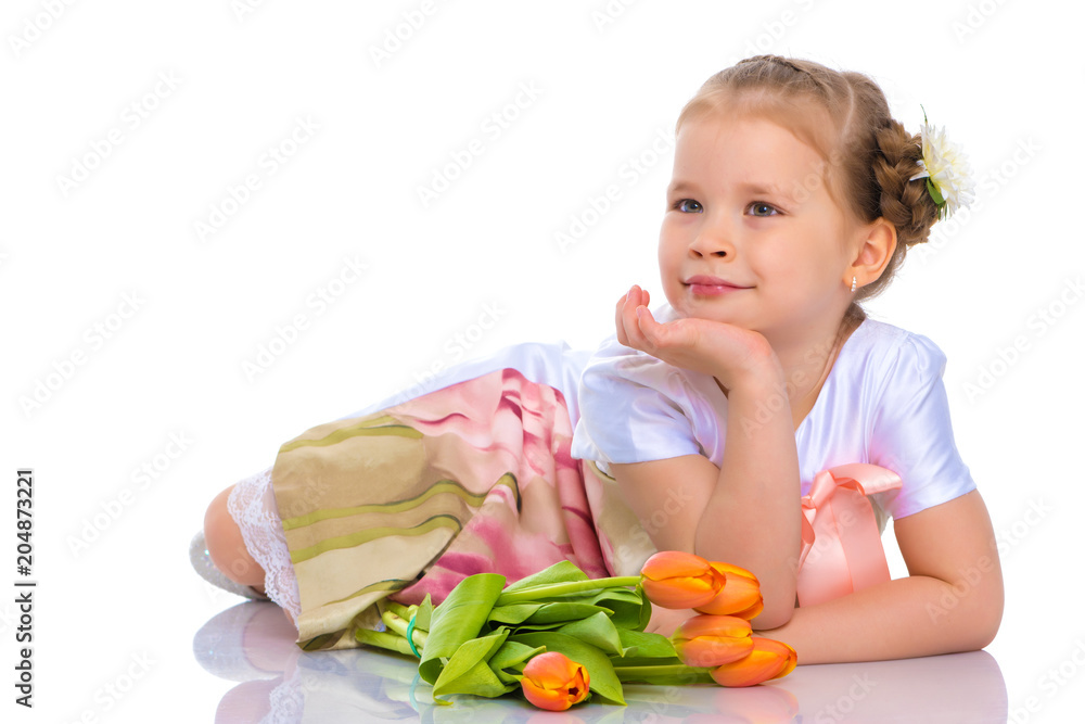 A little girl is lying on the floor with a bouquet of tulips. A little girl is lying on the floor with a bouquet of tulips.