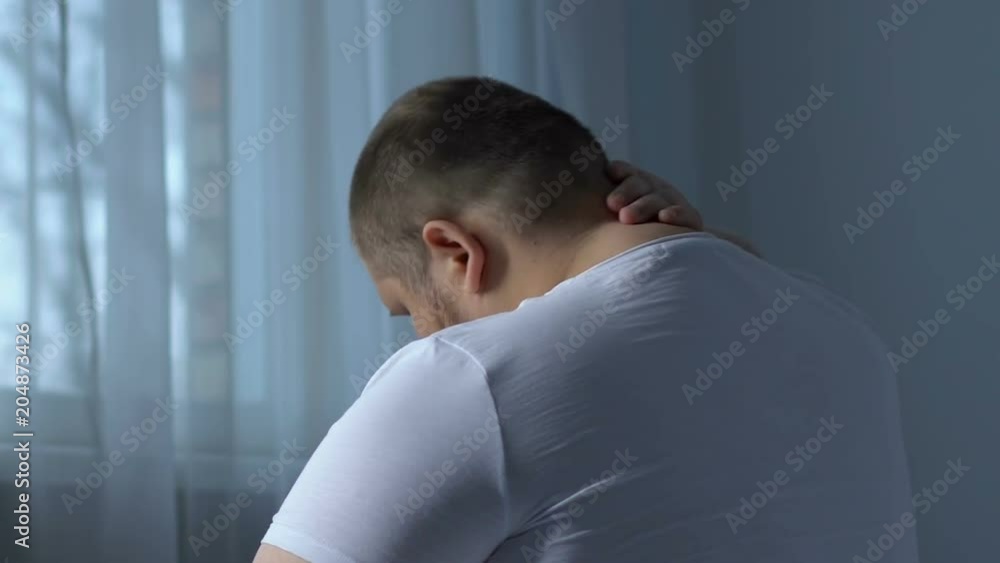 Fat man suffering from neck pain, massaging by hand, sedentary work effect Fat man suffering from neck pain, massaging by hand, sedentary work effect