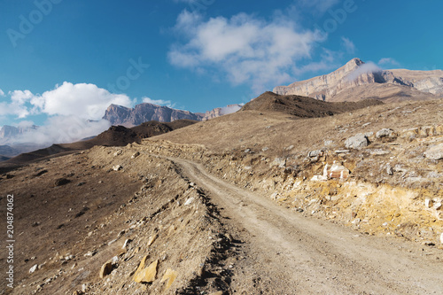 Country road in the mountains against the background of epic rocks