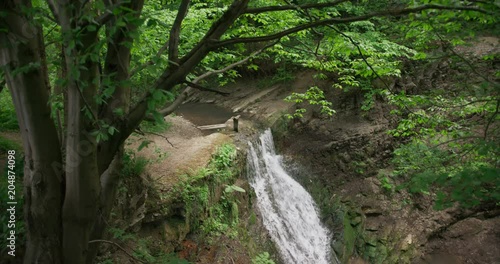 Beautiful waterfall in the wood, spring, tilt down, 4k