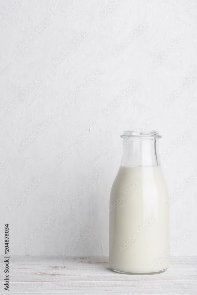 Full glass bottle of milk on white wooden table background vertical compositionl with copy space Full glass bottle of milk on white wooden table background vertical compositionl with copy space