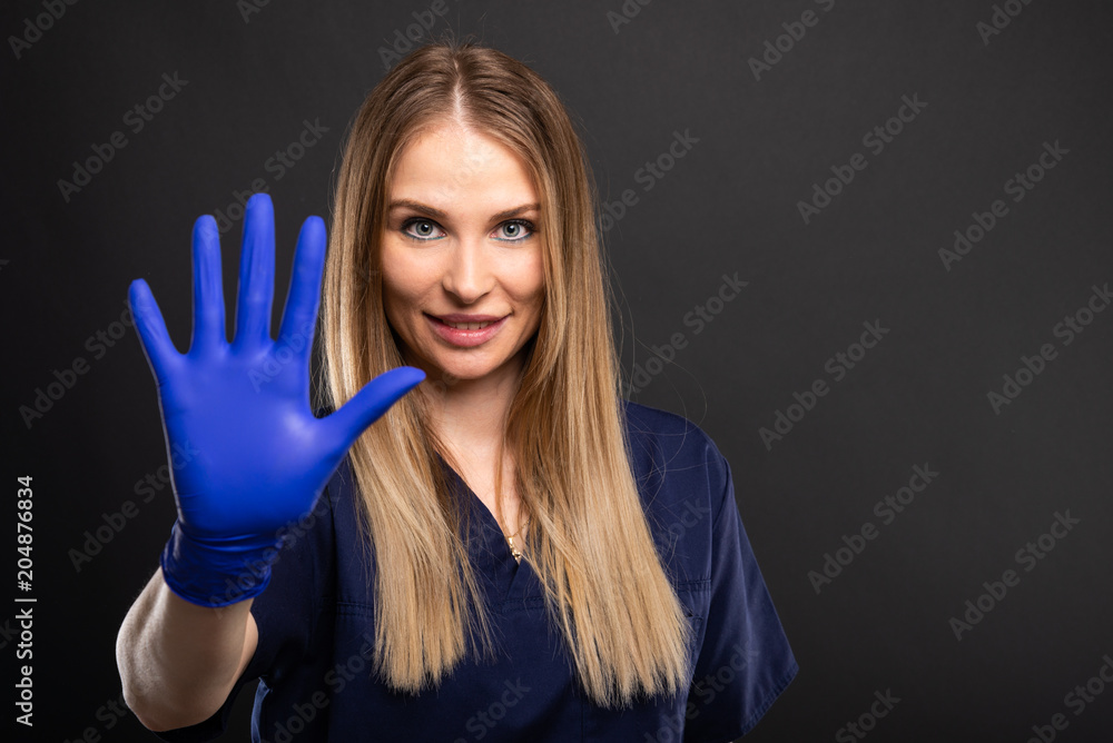 Female dentist wearing scrubs showing showing number five. Female dentist wearing scrubs showing showing number five.