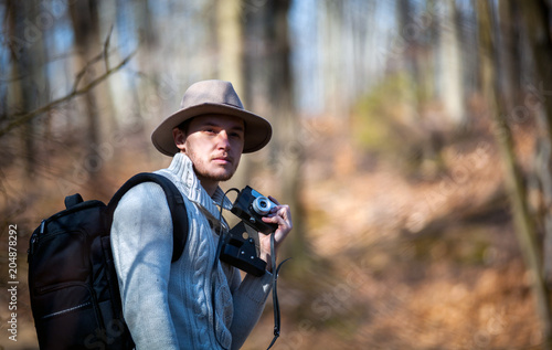 Traveler man with vintage camera and backpack, hipster tourist in forest © leszekglasner