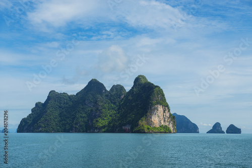 Three boats sailing through tropical group of islands with limestone caves inside in Ao Phang-Nga National Park, Andaman Sea, Thailand.