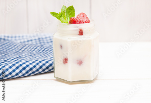 Cream with a strawberry on white wooden background.  